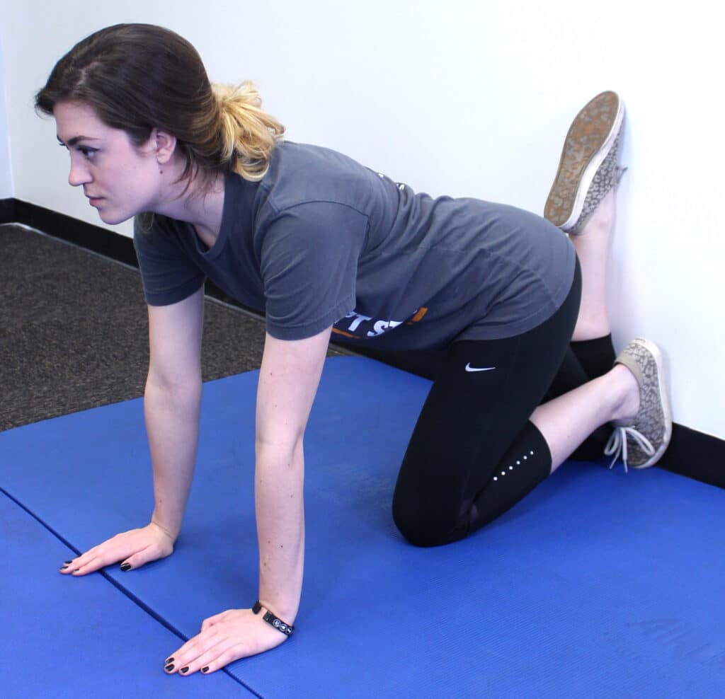 Woman performing knee wall stretch