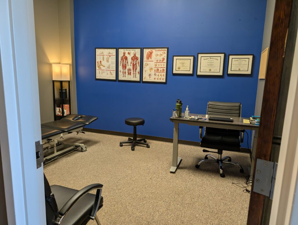 Treatment room with provider's desk at Airrosti Far HIlls