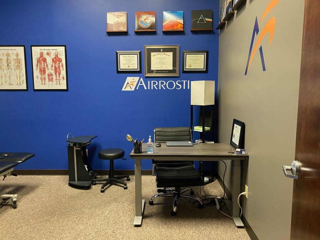 Photo of treatment room at Airrosti Far Hills. Included ACP's desk and accolades.