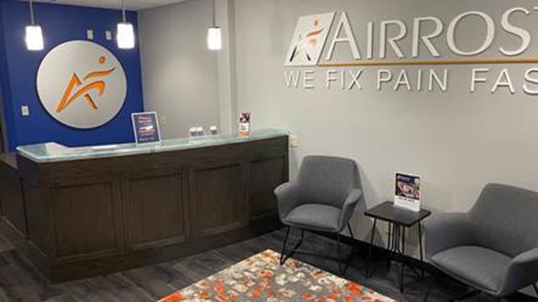 The lobby at Airrosti Bellevue with the front desk and lounge chairs for waiting patients