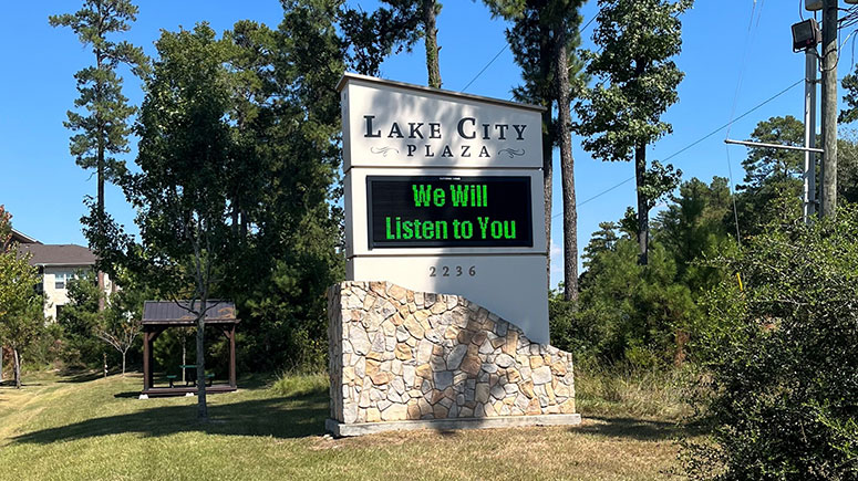 A stone sign visible from the road that says Lake City Plaza, which is the business complex where Airrosti Conroe is located.