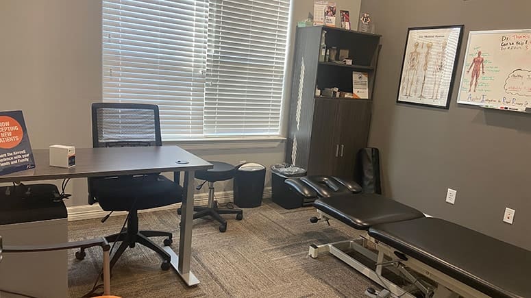 a photo of the treatment room at Airrosti Spring-Klein. The treatment table and provider's desk are both visible