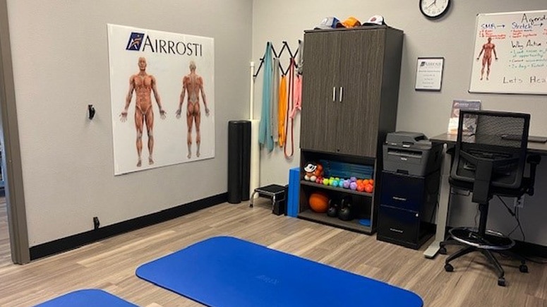 An interior view of the recovery room at Airrosti Tacoma. Exercise mats and equipment can be seen in the room.