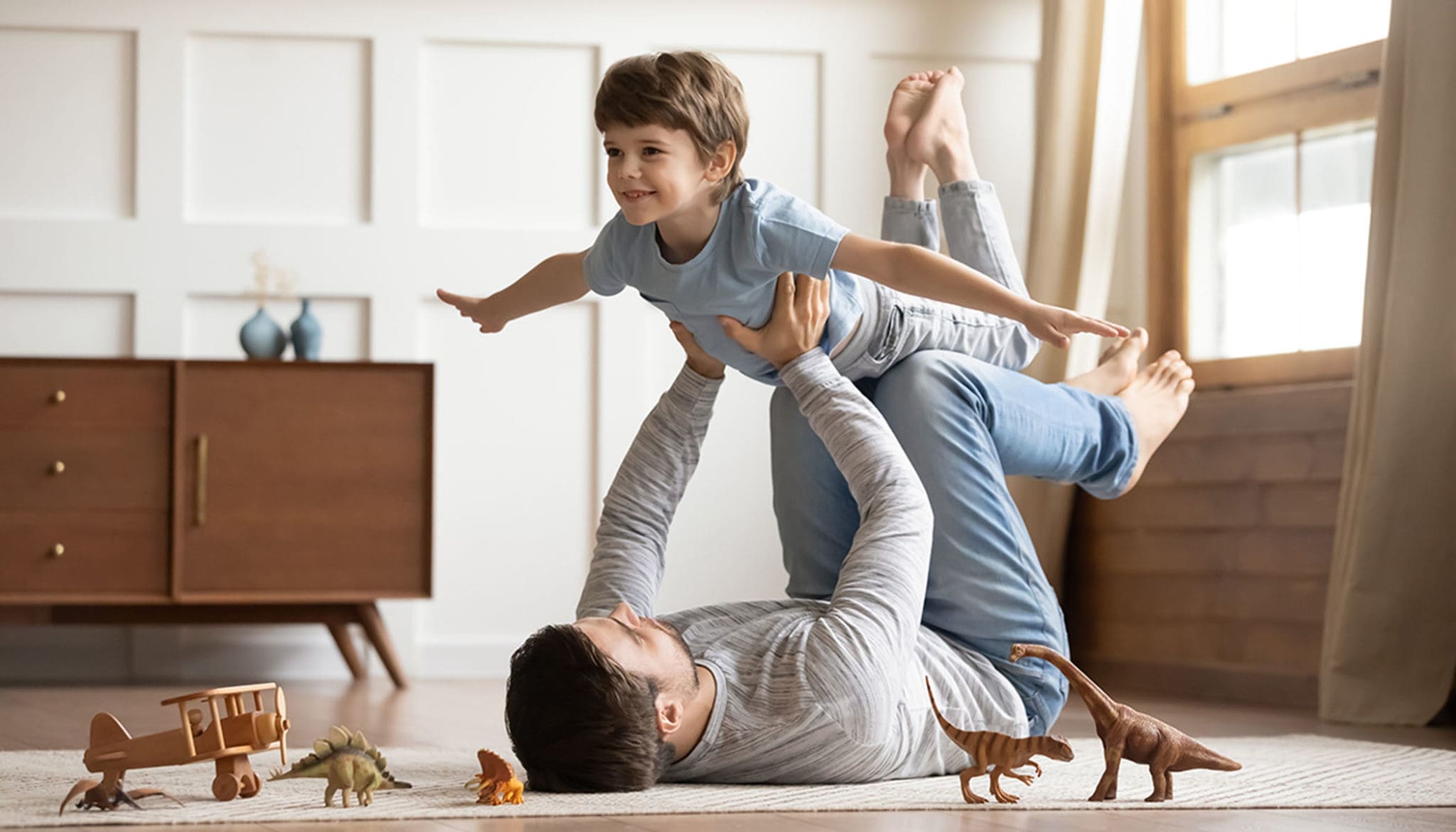Joyful young man father lifting excited happy little son.