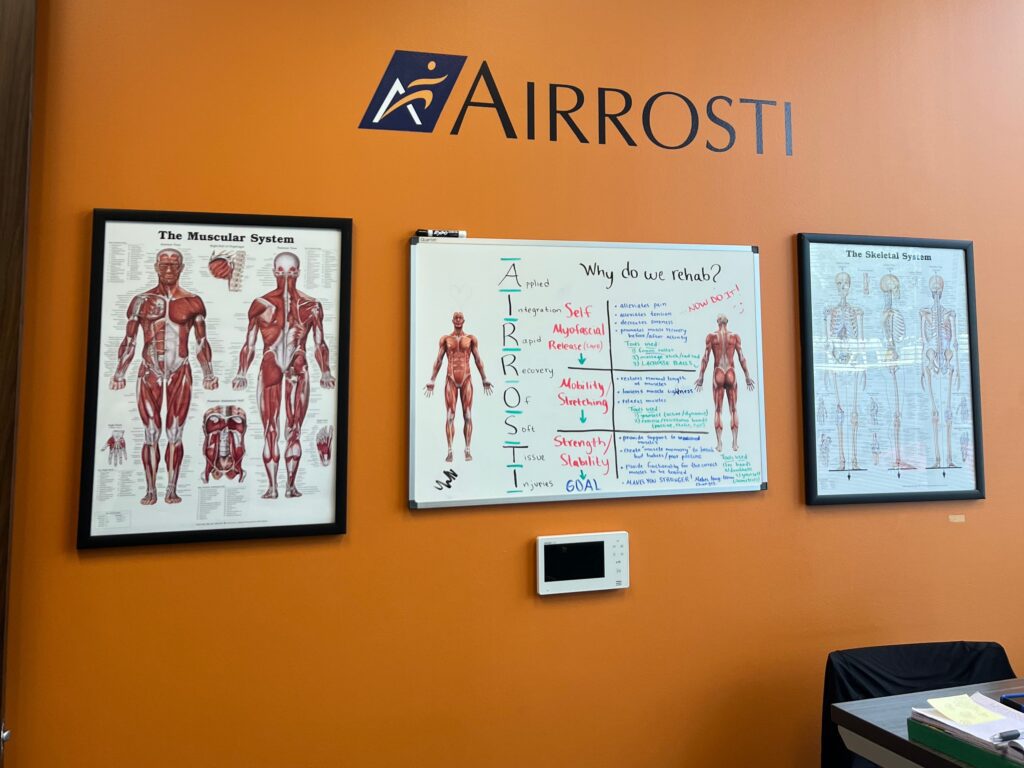 Wall with posters in the treatment room at Airrosti Willowbrook