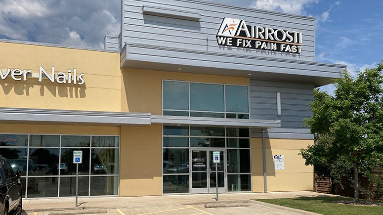 An exterior view of the Airrosti Cedar Park building. It is a corner unit with the Airrosti sign visible.