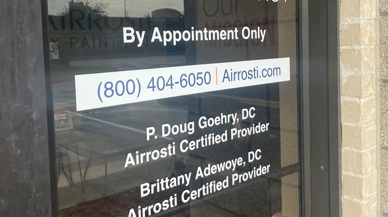 A close up photo of the nameplate on the exterior front door at Airrosti Katy