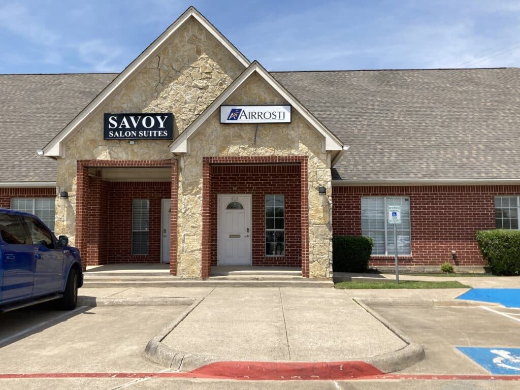 A wide view of the building exterior at Airrosti North Richland Hills in Dallas, TX. The front entrance is right next door to Savoy Salon Suites.