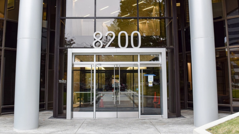 A view of the front entrance to the building where Airrosti Tyson is located. A wide set of glass double doors under exterior address numbers showing 8200.
