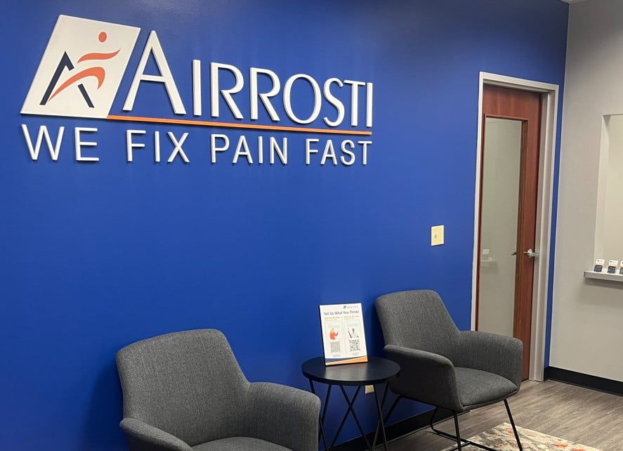 waiting room at the Airrosti Sugarland location with chairs and logo signage