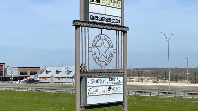 Photo of the exterior marquee of the building that includes the Airrosti logo at Airrosti Burleson. I-35 is visible in the background