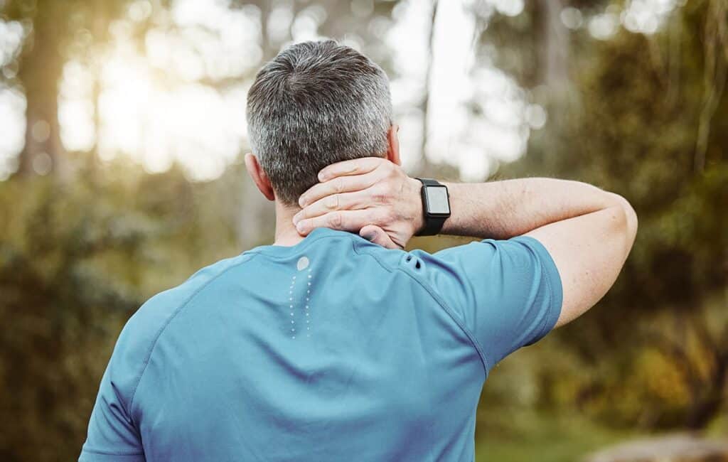 man rubbing the back of his neck in pain