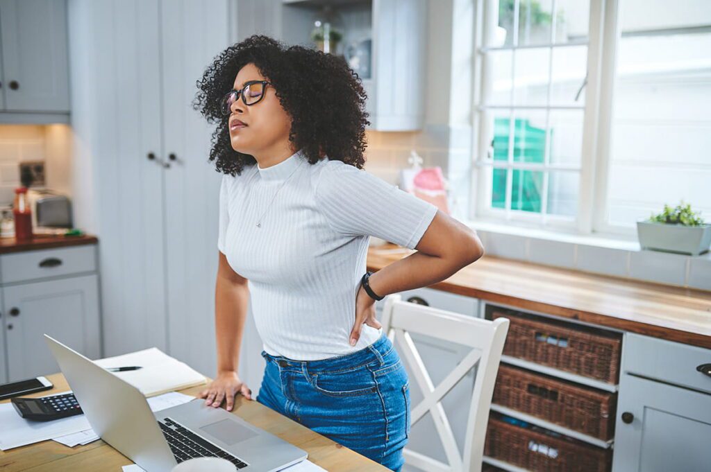 woman standing up, working from home, with back pain
