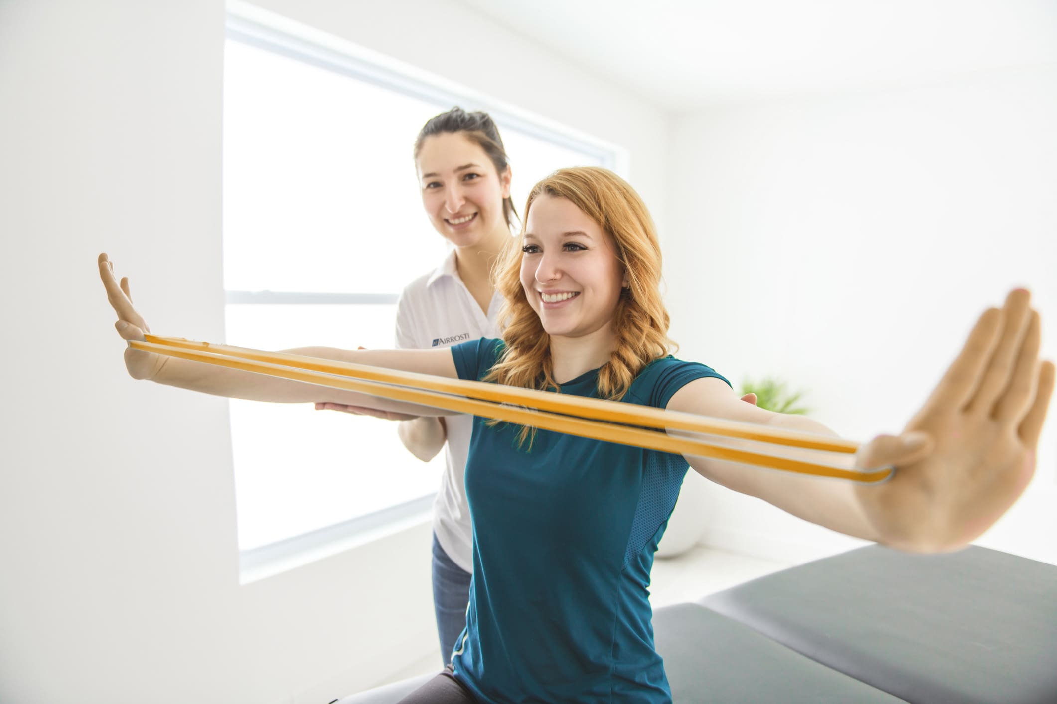 Provider working with patient - helping her complete exercises with bands