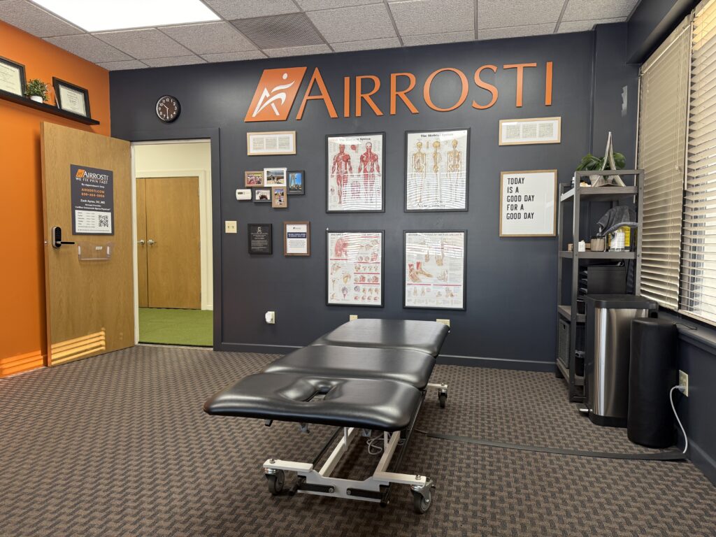 Treatment room at Airrosti Elite with a view of the table and MSK posters on wall