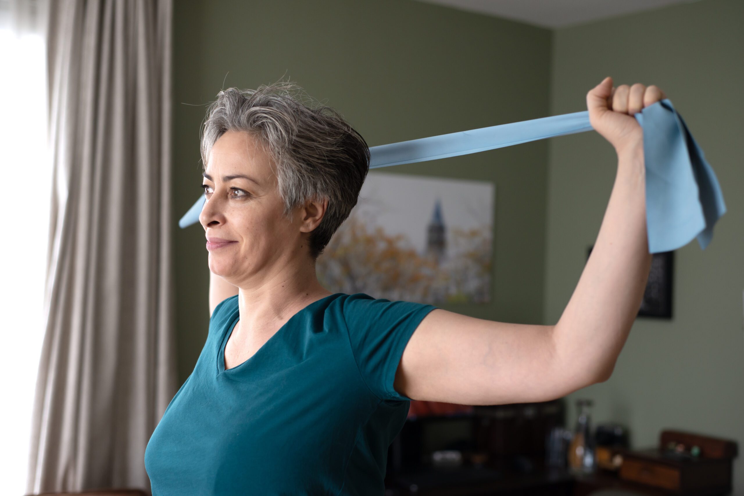 Middle aged woman doing stretching exercises with blue stretch band or gymnastic band