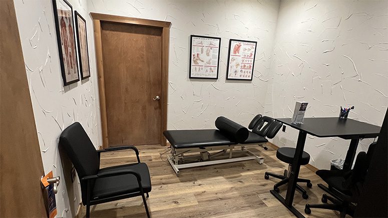 A view inside the treatment room at Airrosti Cedar Hill. A large treatment table dominates the center of the room.